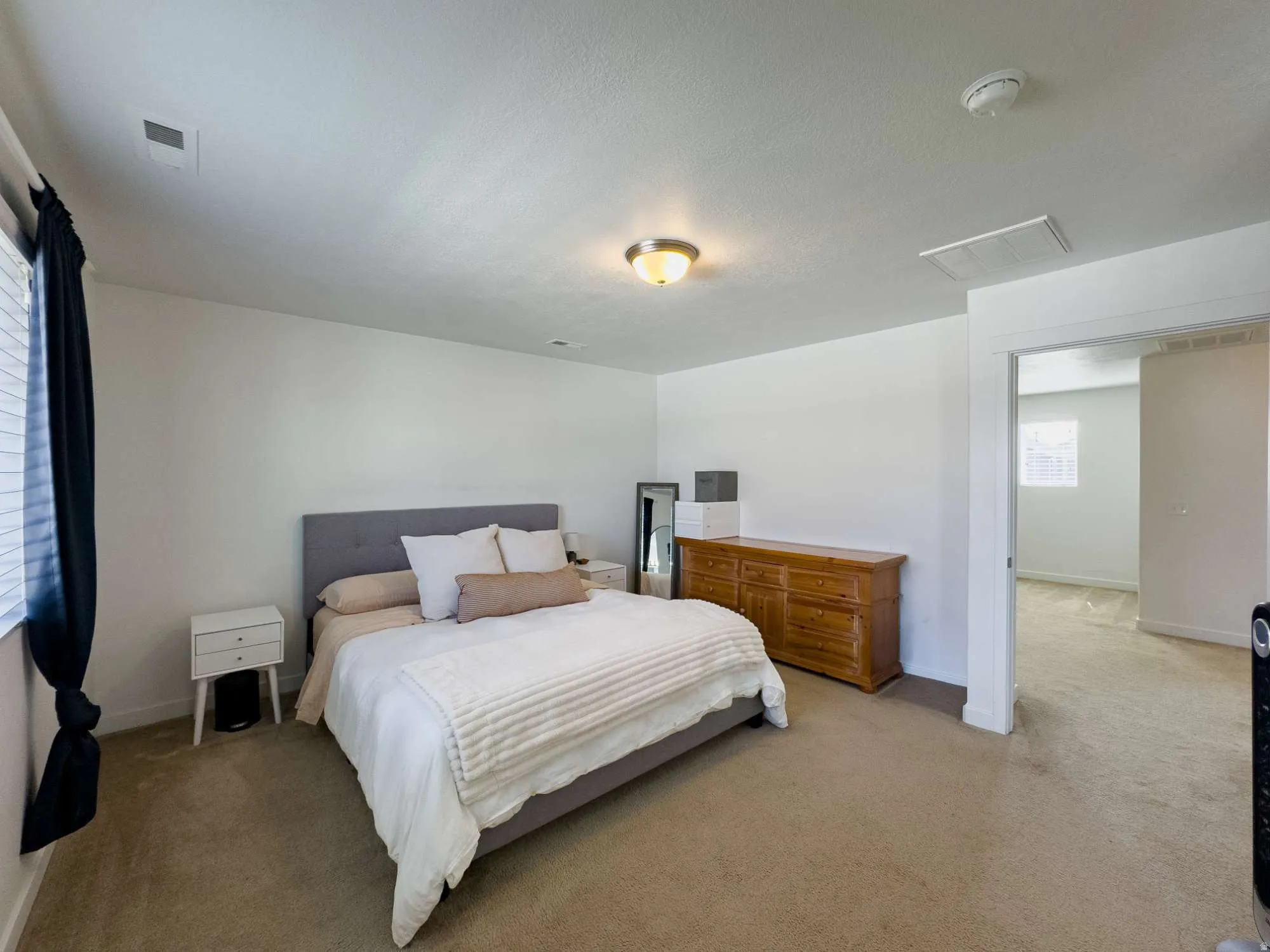 Carpeted interior main bedroom with white walls and a recessed window