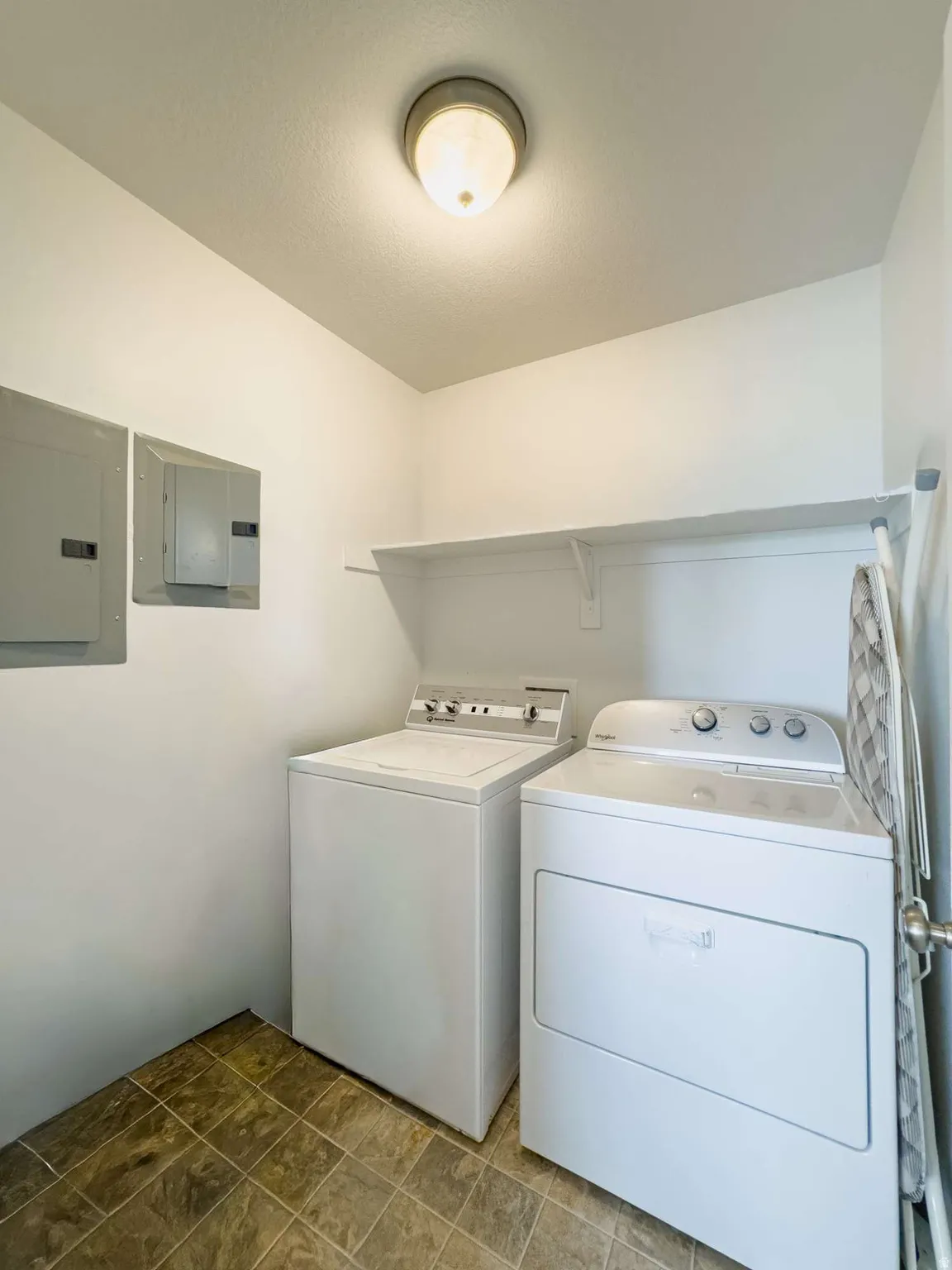 Dedicated laundry room featuring side-by-side washer and dryer appliances, upper shelving for storage, recessed ceiling lighting, tile flooring, and dual mirrored medicine cabinets for convenient organization and functionality
