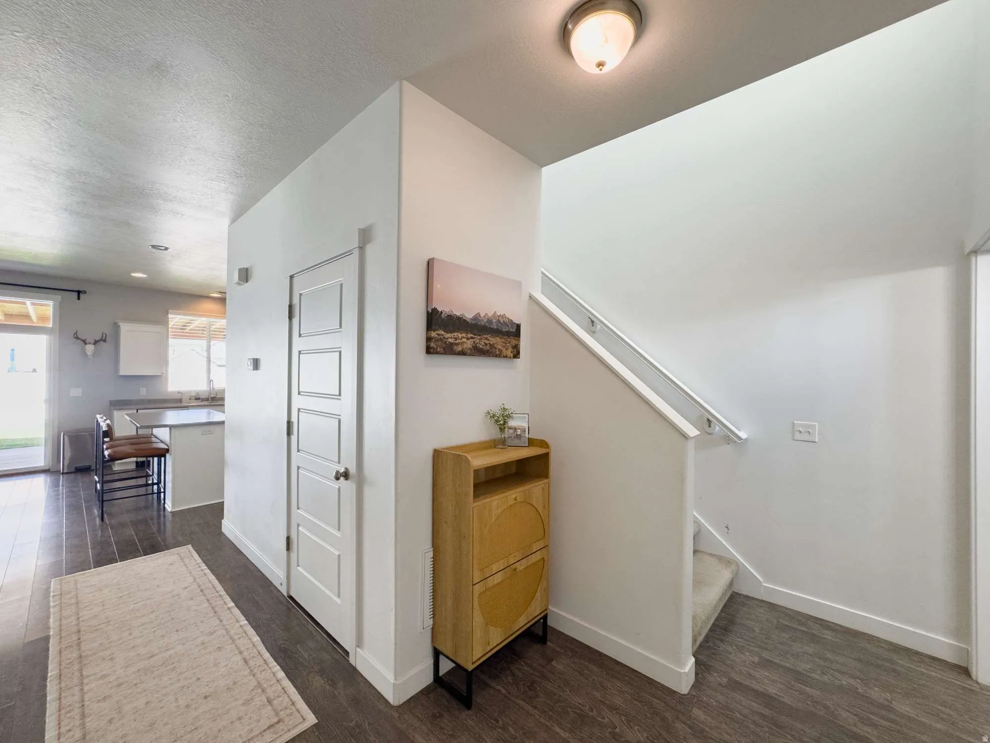 Welcoming foyer featuring gleaming wood-finish flooring, crisp white walls, and abundant natural light from multiple windows