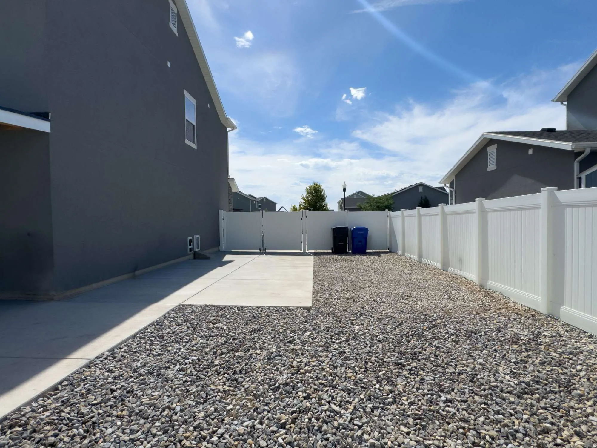 Defined side yard featuring gravel landscaping, a concrete RV pad, and a white privacy fence