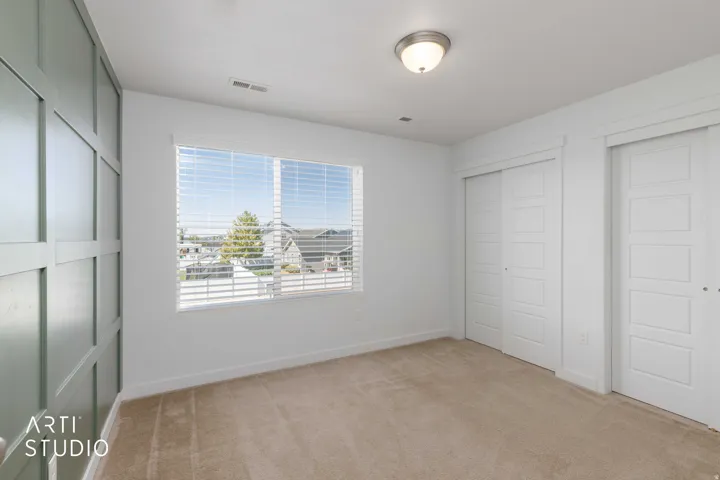 Board and batten accent wall, neutral carpet flooring, sliding panel closet doors, window with blinds, and flush mount ceiling light