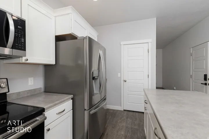 White shaker-style cabinetry, stainless steel appliances, durable wood-finish flooring, and light-toned countertops