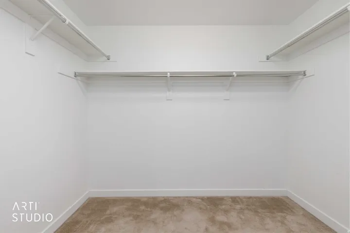 Primary Bedroom Closet featuring neutral wall paint, light-toned carpeting, and integrated shelving with hanging rods