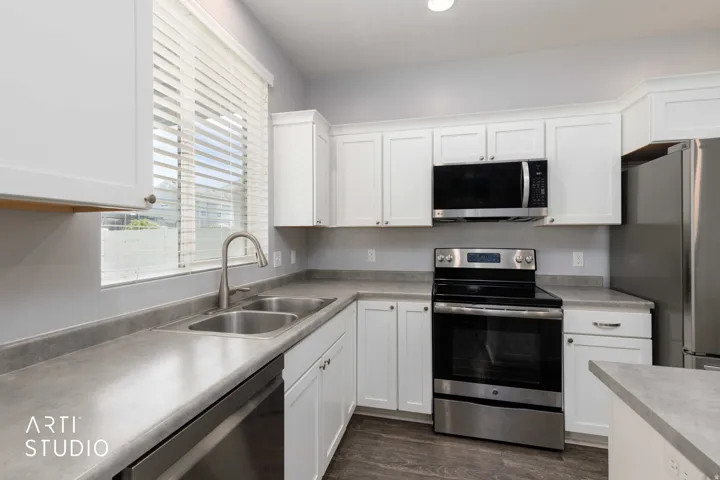 Kitchen featuring white cabinetry, stainless steel appliances, a double basin sink, and wood-finish flooring