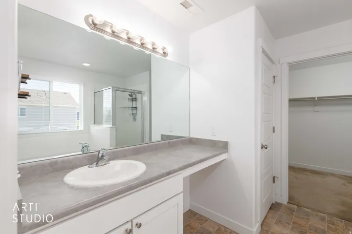 Primary bedroom vanity with an integrated sink, polished chrome faucet, and expansive mirror