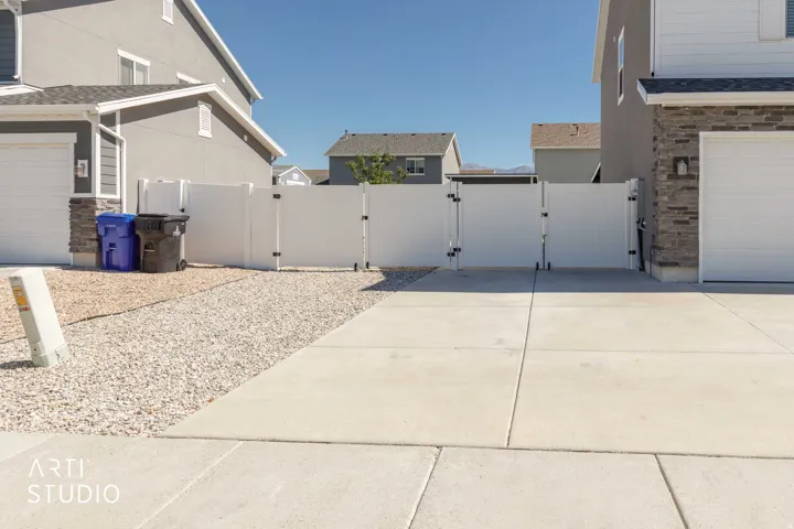 Concrete driveway with a gravel side yard and white vinyl fencing