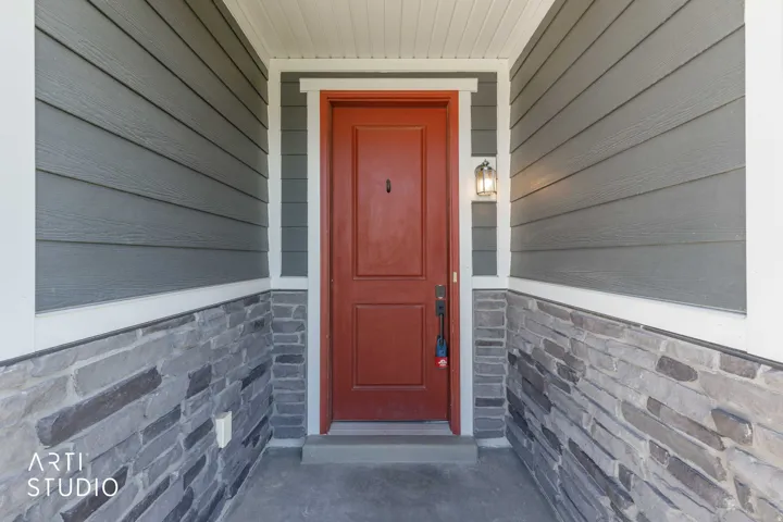 Front entry with a paneled door, exterior wall lantern, stone veneer, and horizontal siding