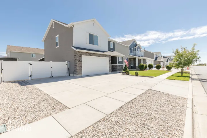 Two-story residence featuring a mixed-material facade with stone accents, an attached garage, and a concrete driveway