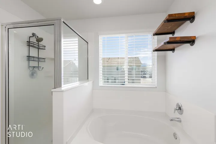 Primary Bedroom Walk-in shower with a glass enclosure, built-in bathtub, window with blinds, and two wall-mounted wood-finish shelves