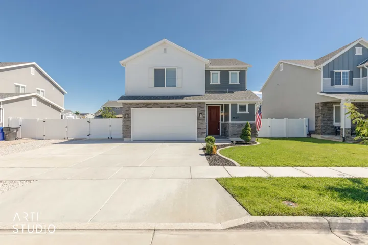 Two-story residence featuring a stone and siding exterior, an attached two-car garage, and a concrete driveway
