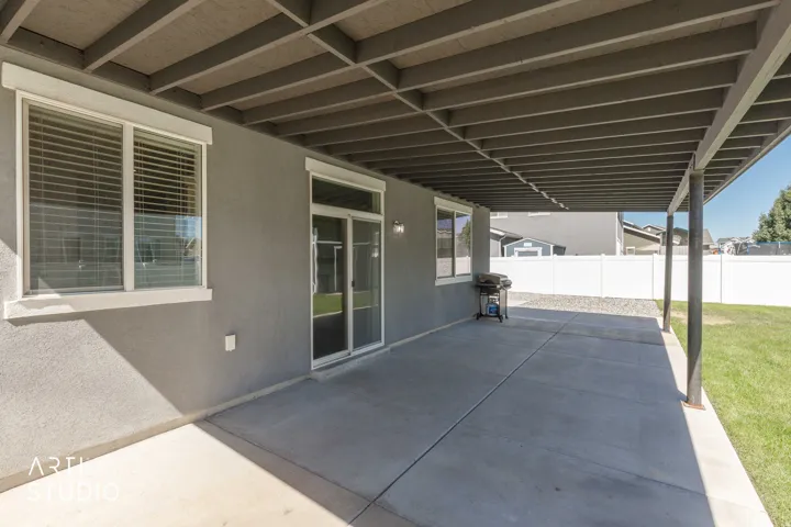 Covered concrete patio with stucco exterior and sliding glass door access