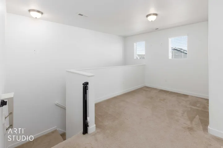 Carpeted landing featuring two windows with horizontal blinds and two ceiling-mounted light fixtures