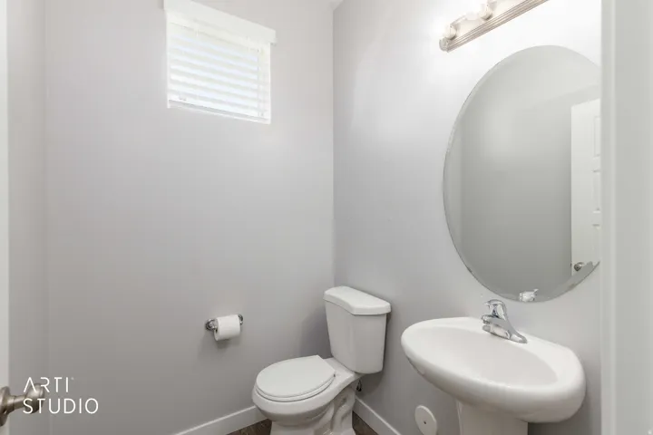 Pedestal sink with chrome faucet, oval wall mirror, and vanity light fixture