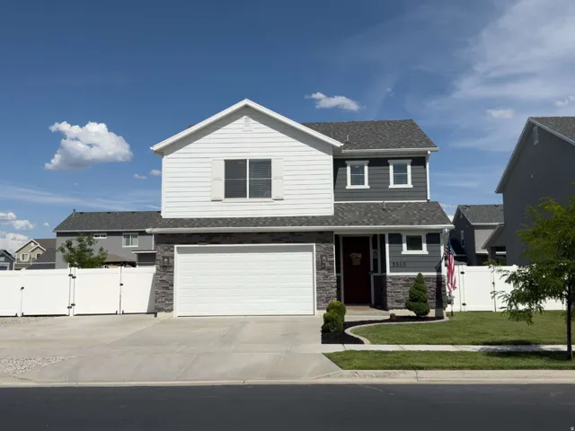 Two-story residence featuring a gray and white exterior with stone accents