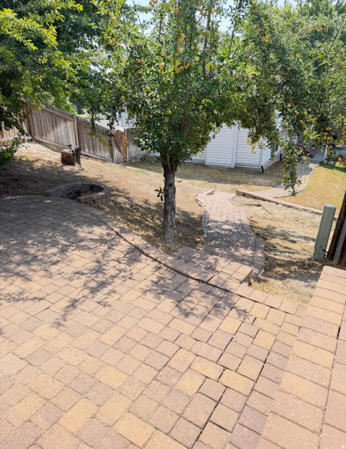 Tiered paver patio with steps, a paver pathway, and a built-in fire pit