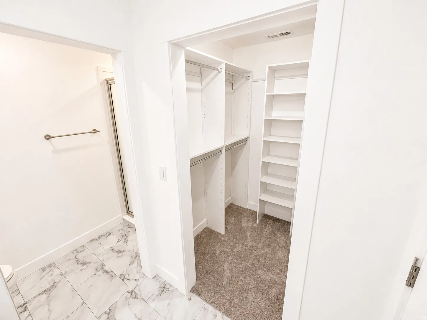 Master Walk-in closet with carpet flooring, white built-in shelving, and hanging rods