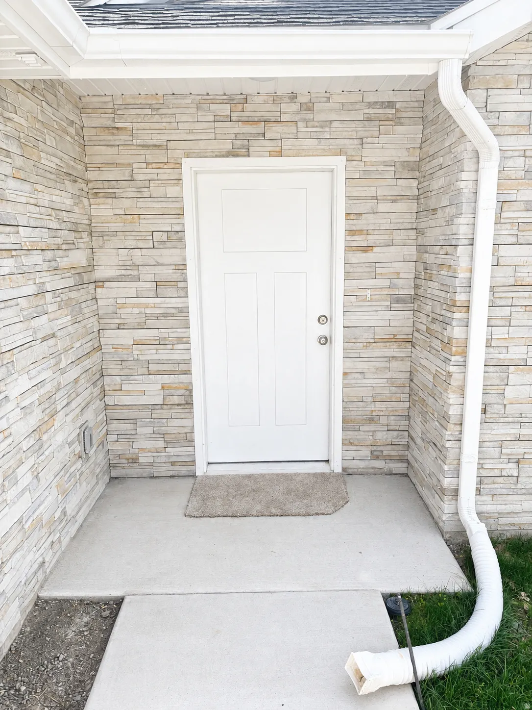 White paneled entry door set within a stacked stone veneer facade
