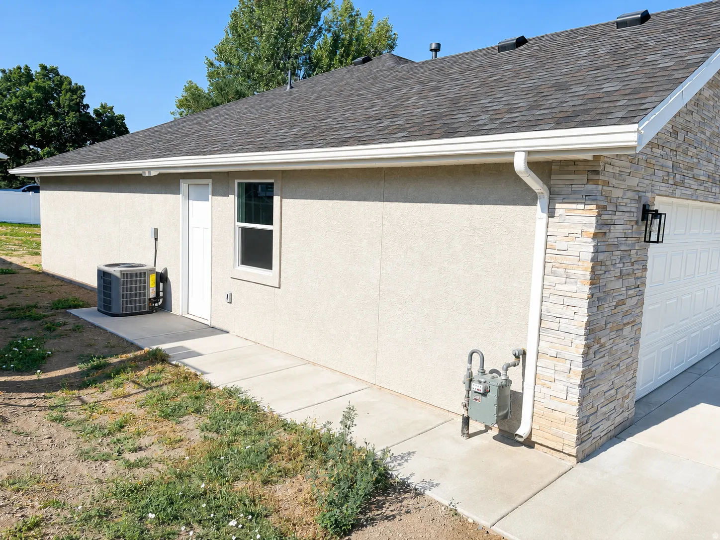 Exterior featuring stacked stone accents, stucco siding, a white overhead garage door, and a concrete walkway