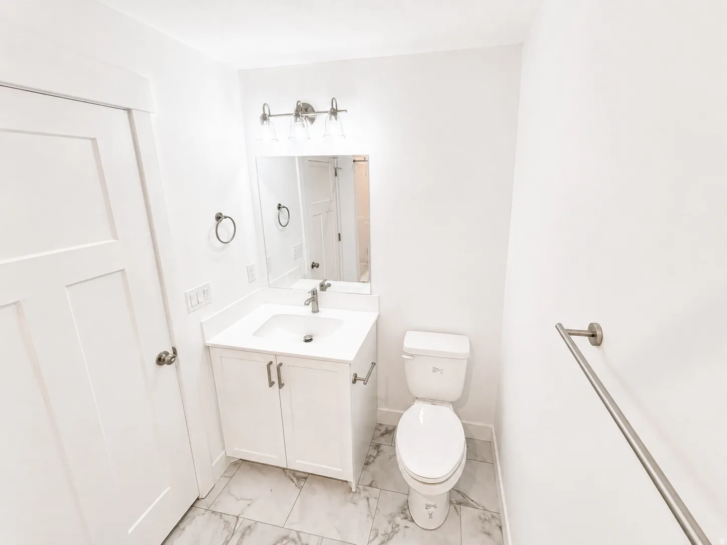 Bathroom featuring a white vanity with an integrated sink, polished chrome faucet, and a rectangular wall mirror