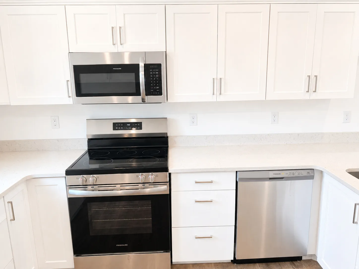Kitchen featuring white shaker-style cabinetry, light-colored countertops, and stainless steel appliances