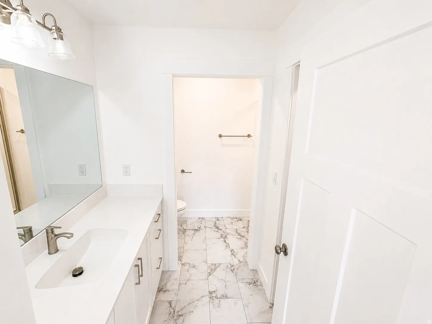 Master bathroom vanity area featuring a wide sink basin, brushed nickel faucet, large wall-mounted mirror, and overhead lighting fixture