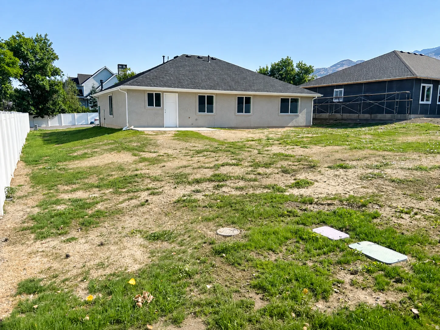 Rear exterior featuring a stucco finish, dark shingle roof, and multiple windows