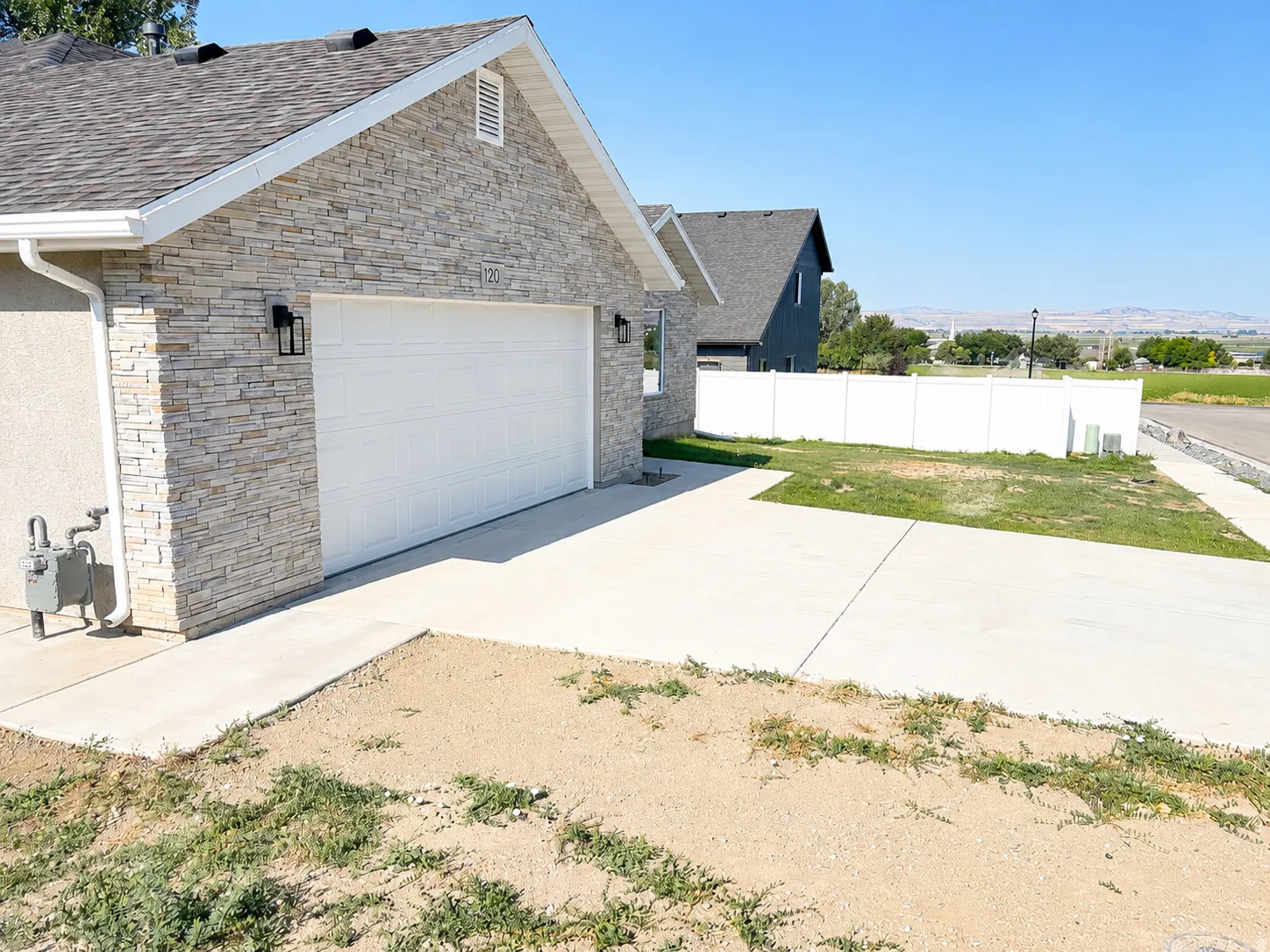 Front exterior featuring stacked stone accents, a two-car garage with overhead door, and contemporary outdoor lighting fixtures