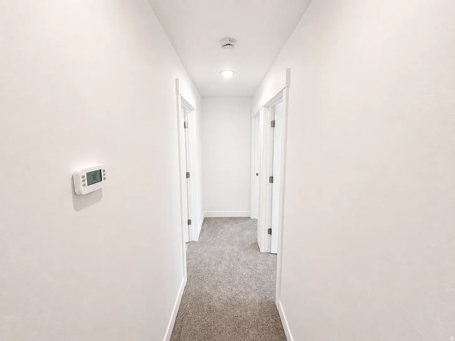 Hallway featuring neutral-toned carpet, white walls, and recessed lighting