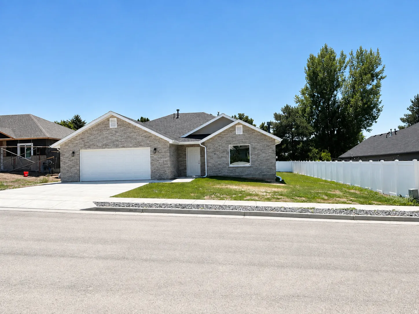 Contemporary single-story residence with a light gray brick exterior, an attached two-car garage, and a dark shingled roof