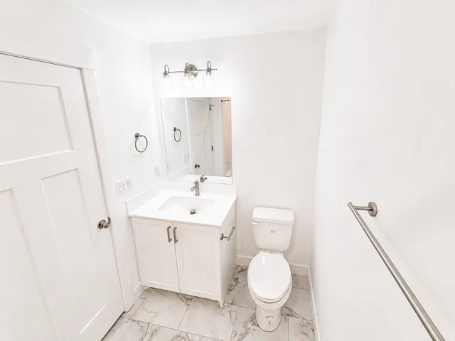 Bathroom featuring a white vanity with an integrated sink, polished chrome faucet, and a rectangular wall mirror