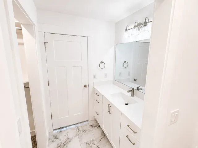 Master bathroom white vanity with integrated sink, brushed nickel faucet, and quartz countertop