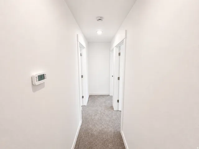 Hallway featuring neutral-toned carpet, white walls, and recessed lighting
