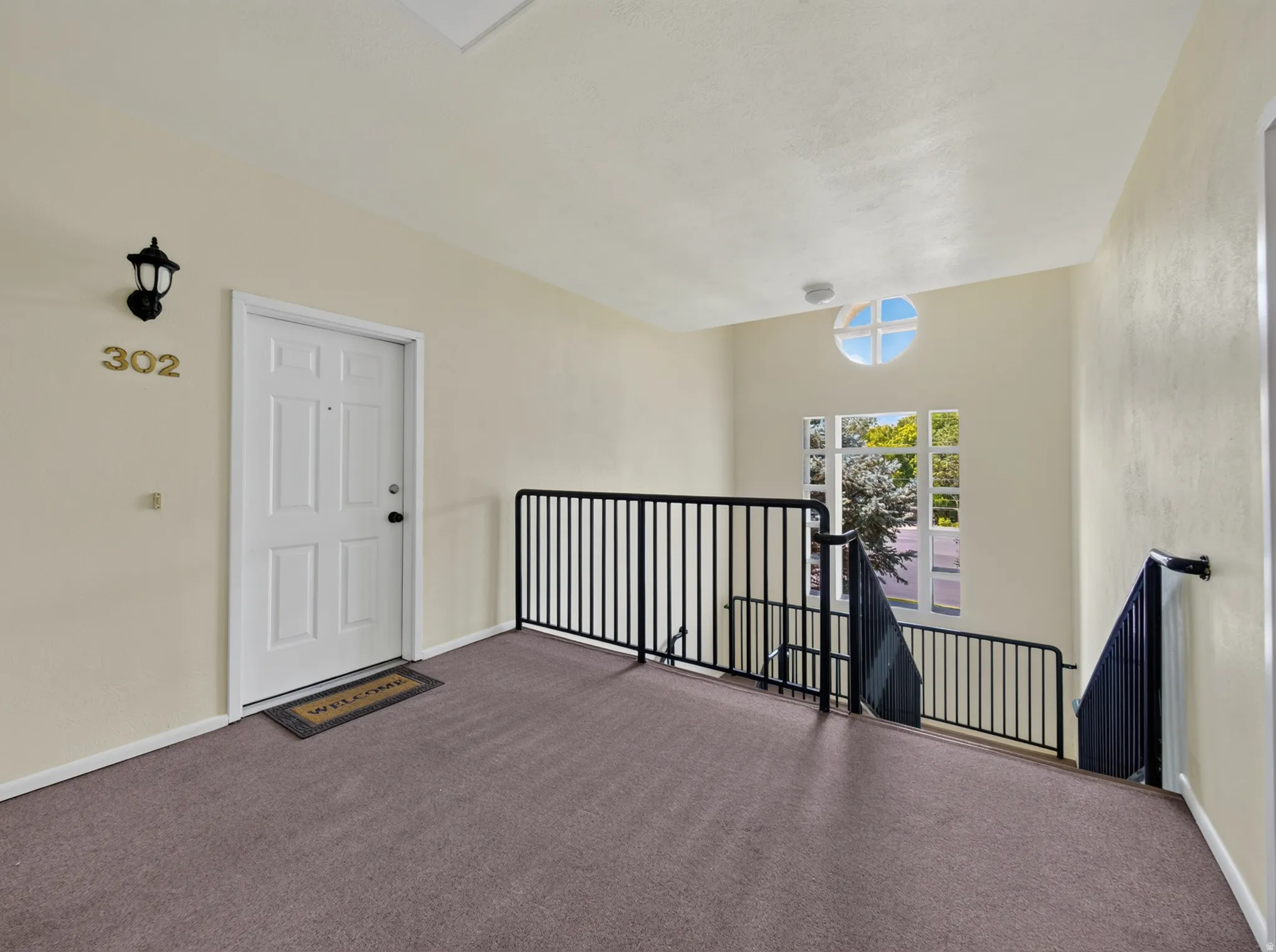 Entryway featuring a white paneled door, wall-mounted lantern light fixture, and neutral carpeting