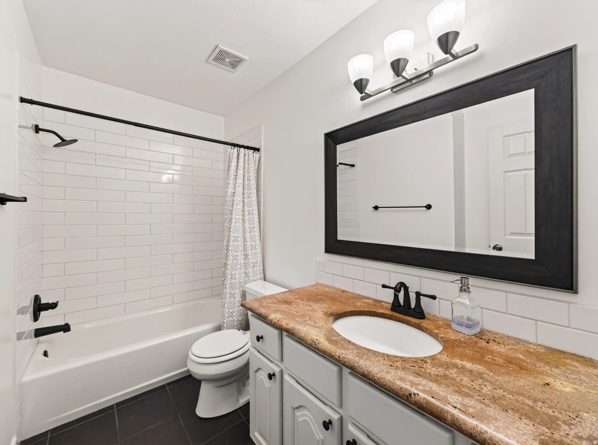 Bathroom featuring a vanity with a stone-finish countertop, undermount sink, and black-finish faucet