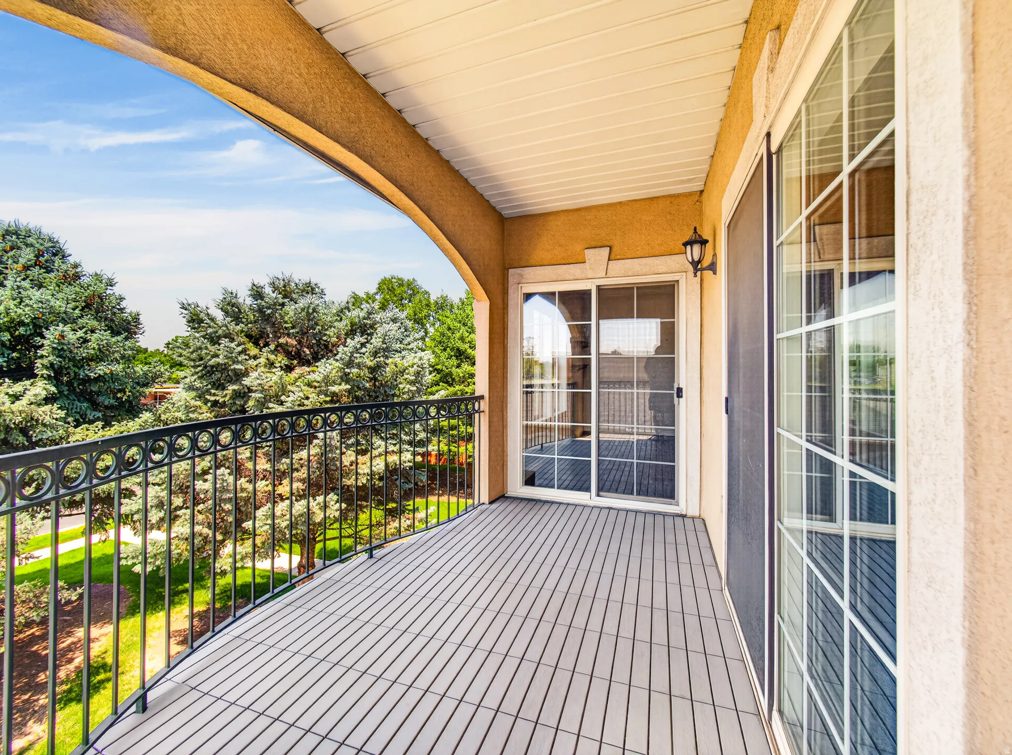 Spacious balcony featuring composite decking and decorative wrought iron railing