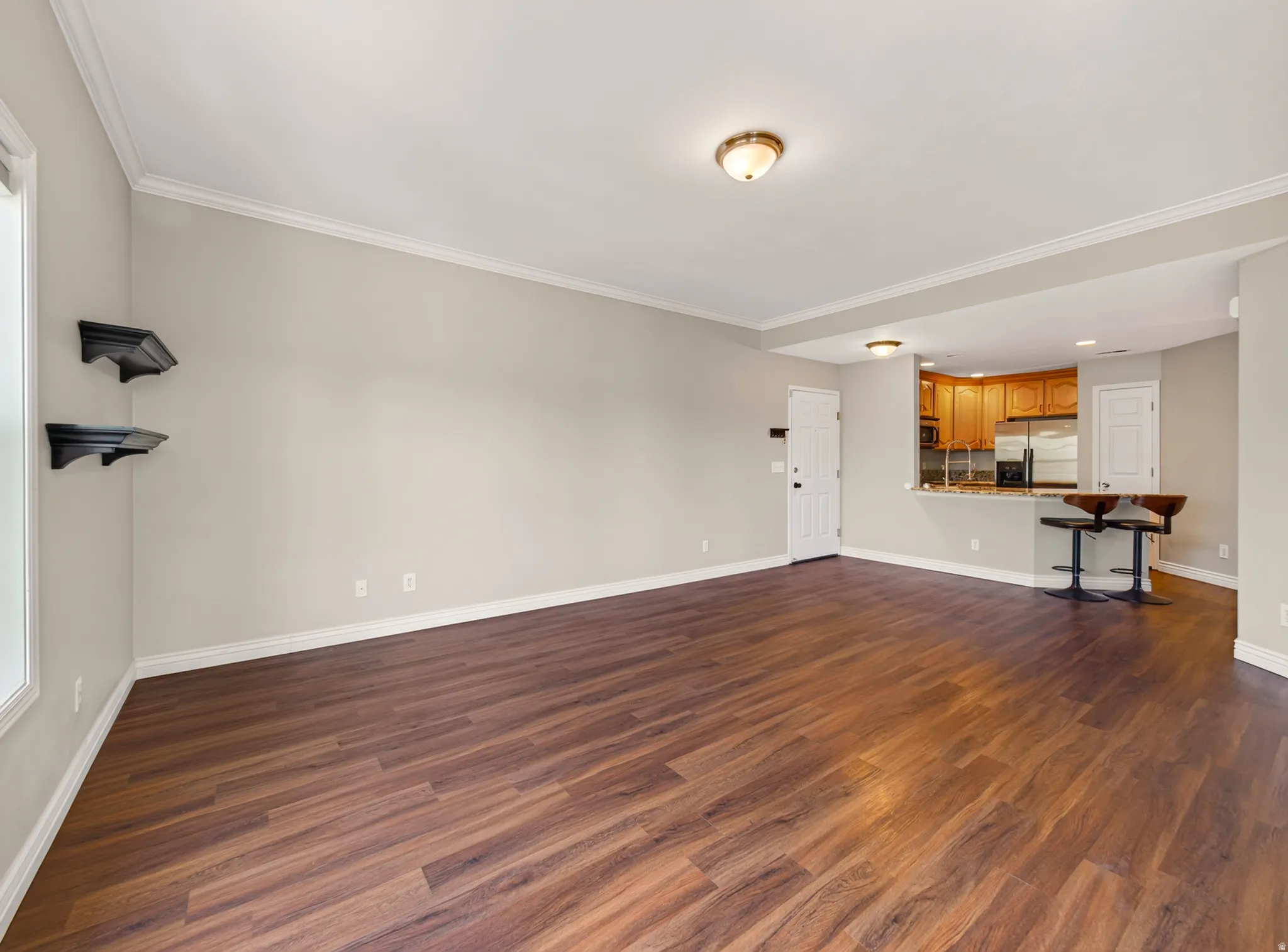 Open-concept living space featuring wood-finish flooring, crown molding, and a neutral wall palette