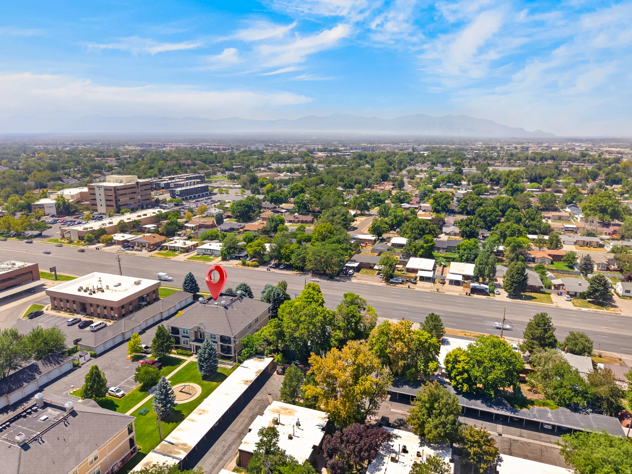 Aerial overview showcasing a multi-story building with a dark roof and surrounding green spaces