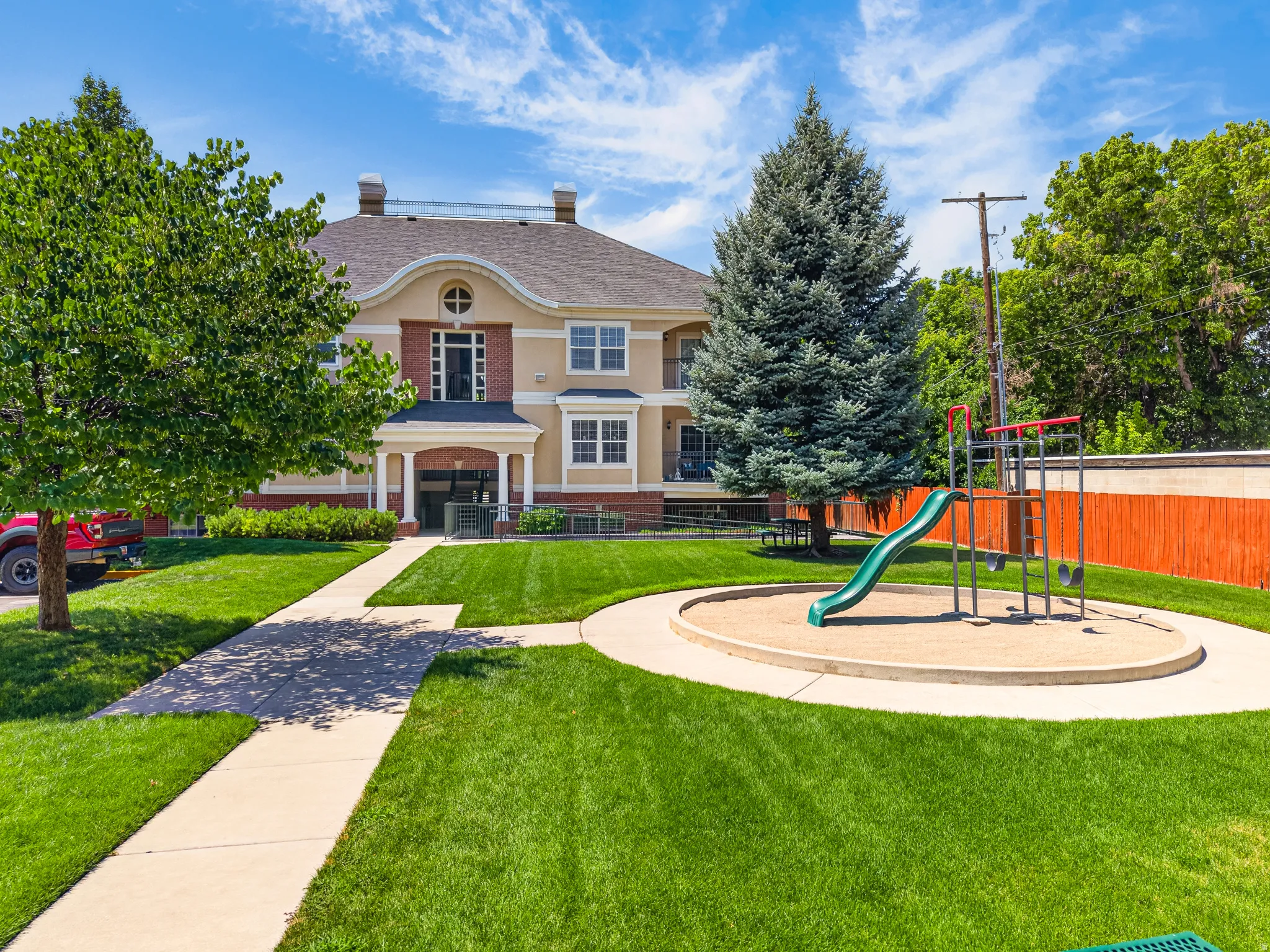 Manicured green lawn surrounding a dedicated sand play area with a slide