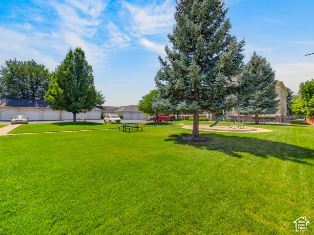 Expansive green space featuring a picnic area, mature trees, and a playground with a slide and climbing structure