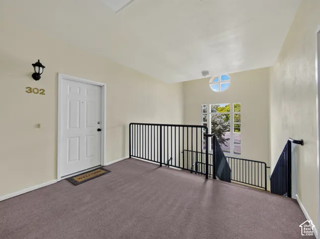 Entryway featuring a white paneled door, wall-mounted lantern light fixture, and neutral carpeting