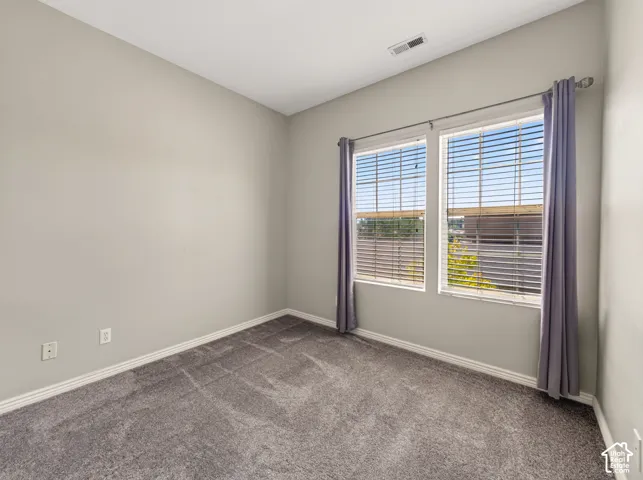 Bright bedroom offering neutral wall finishes, plush carpeting, and abundant natural light from dual glass doors with horizontal blinds and coordinating curtains