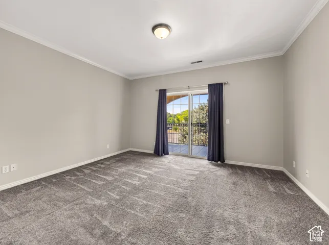 Spacious interior featuring a sliding glass door, crown molding, baseboards, recessed ceiling light, and gray carpeting