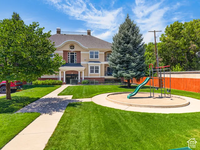 Manicured green lawn surrounding a dedicated sand play area with a slide
