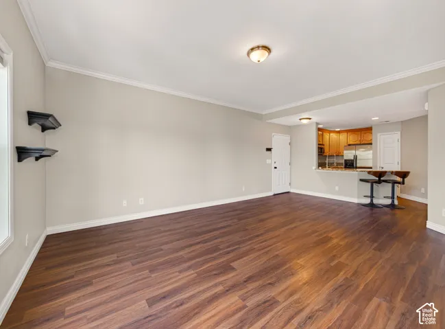 Open-concept living space featuring wood-finish flooring, crown molding, and a neutral wall palette