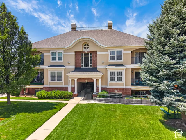 Elegant two-story Colonial residence featuring a cream and brick exterior with symmetrical architecture, arched entry portico with dark wood doors, and multiple multi-pane windows