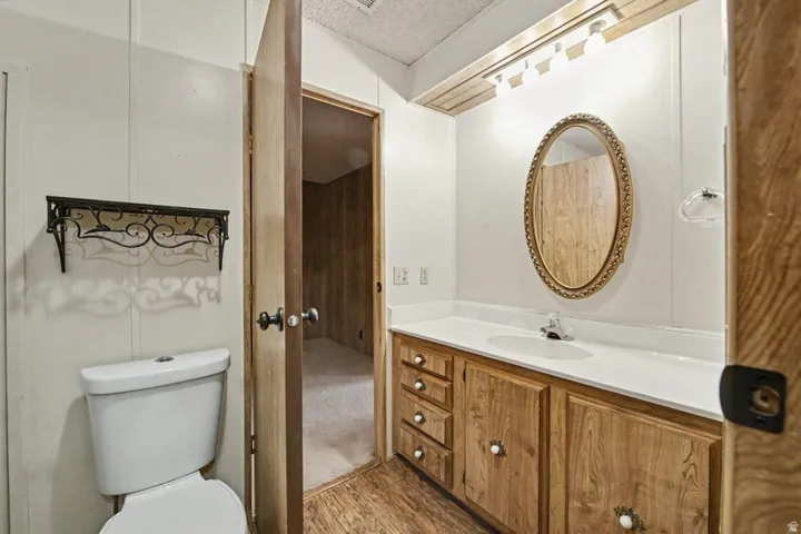 Bathroom featuring a wood-finish vanity with an integrated sink, a white countertop, and an oval mirror with a decorative frame