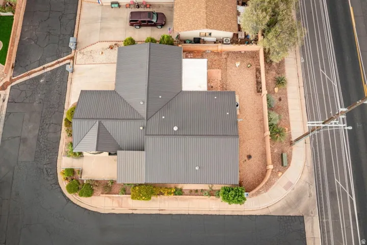 Property featuring a multi-gabled metal roof, concrete driveway, and landscaping