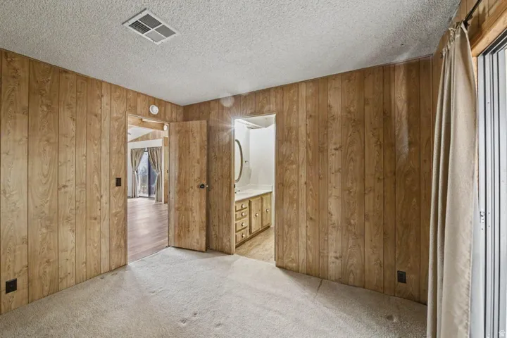 Bedroom with wood-panel walls and light-toned carpeting
