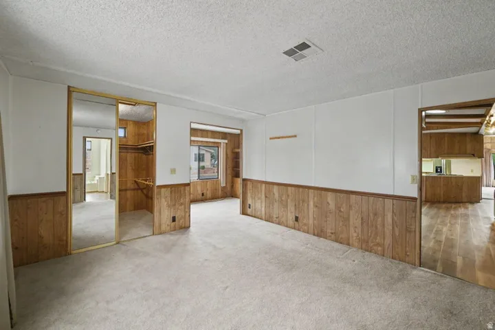 Carpeted interior with wood paneling and white walls