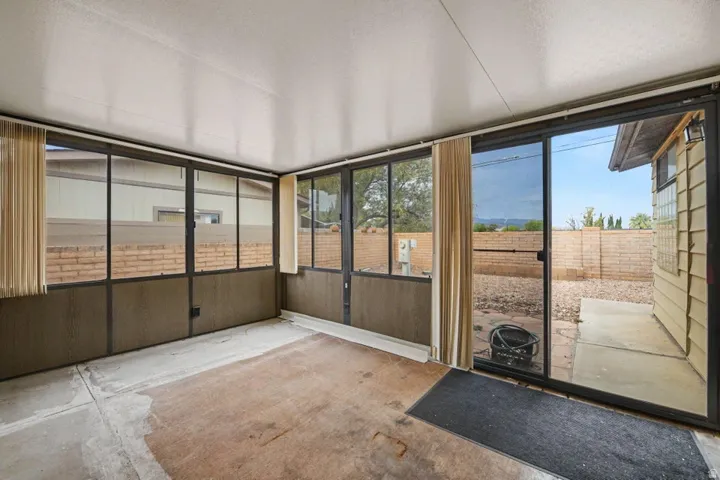 Screened-in patio space featuring full-height aluminum-framed windows and a sliding glass door